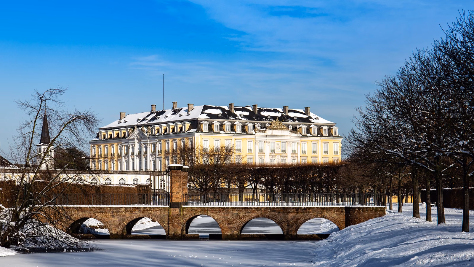 Schloss Augustusburg in Brühl im Winter mit Schnee und Brücke im Vordergrund
