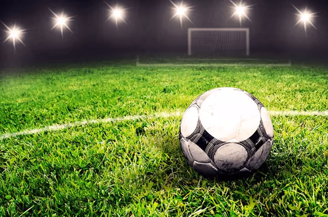 Fussball auf dem Rasen im Flutlicht vor einem Tor